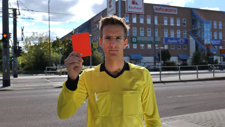Schiedsrichter Julius Neumann hält vor dem Südstadt Center in Halle eine rote Karte in die Kamera