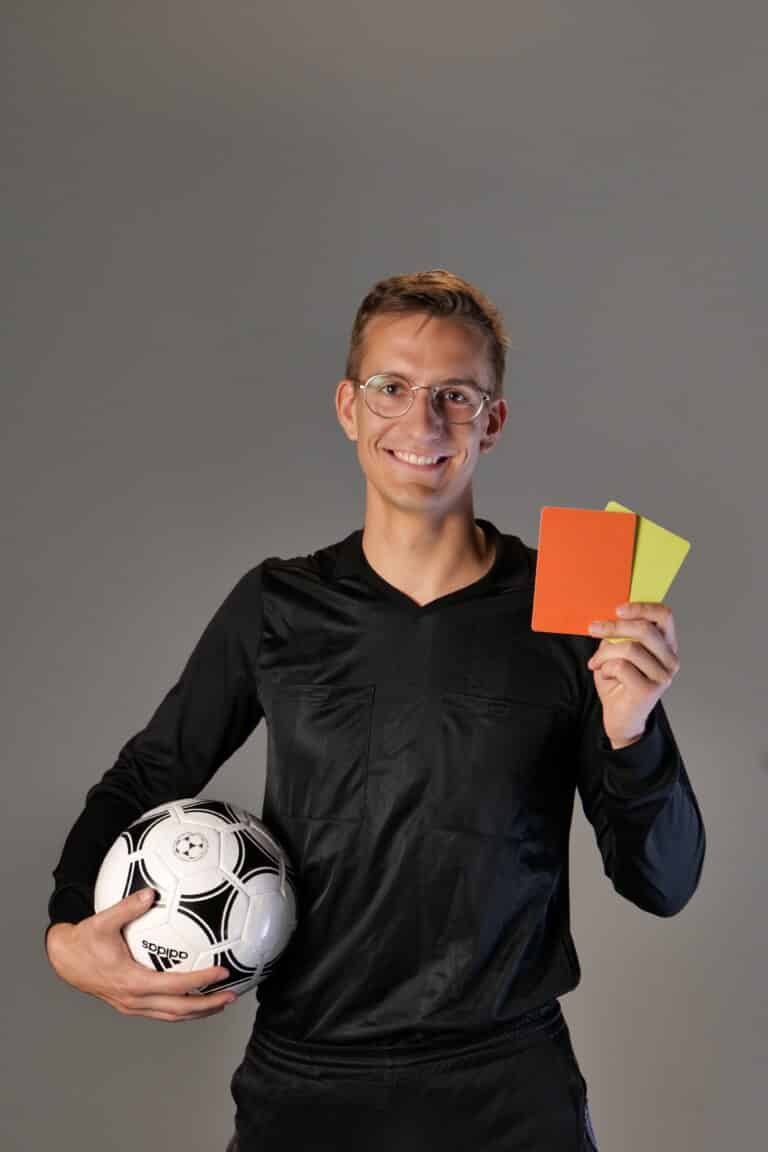 Julius Neumann hält als Landtagskandidat Fußball und gelbe sowie rote Karte in die Kamera